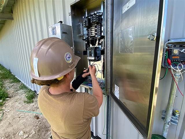 Elektrik panosuna kablo bağlayan teknisyen